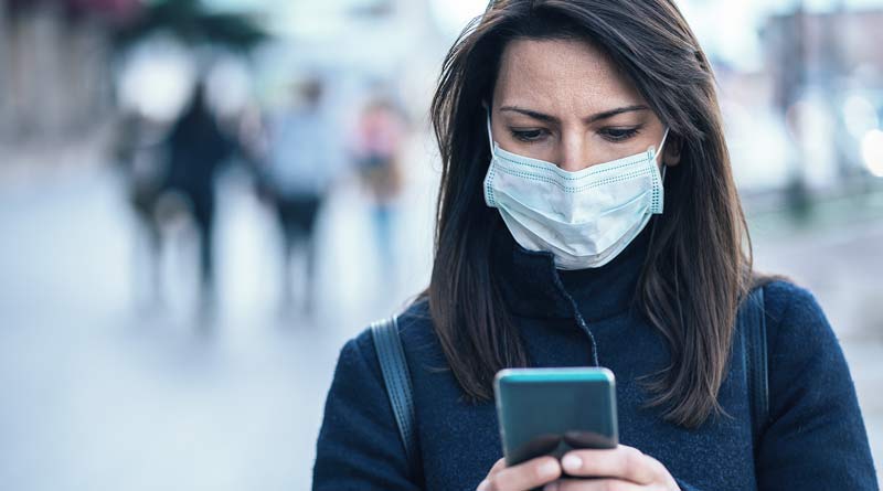 Woman wearing face mask and having telehealth appointment on phone